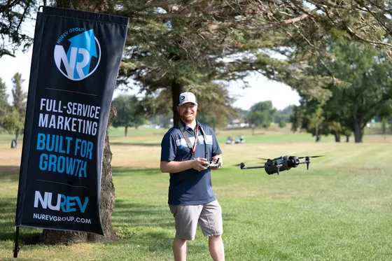 David Vanden Hull flying NUREV’s drone at a golf event, beside a NUREV Group banner